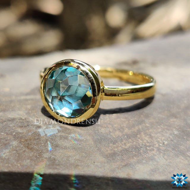 Solitaire engagement ring featuring aqua moissanite and handcrafted design.
