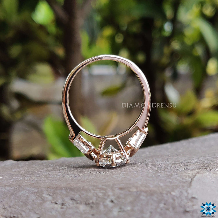Custom rose gold engagement ring with three moissanite stones.
